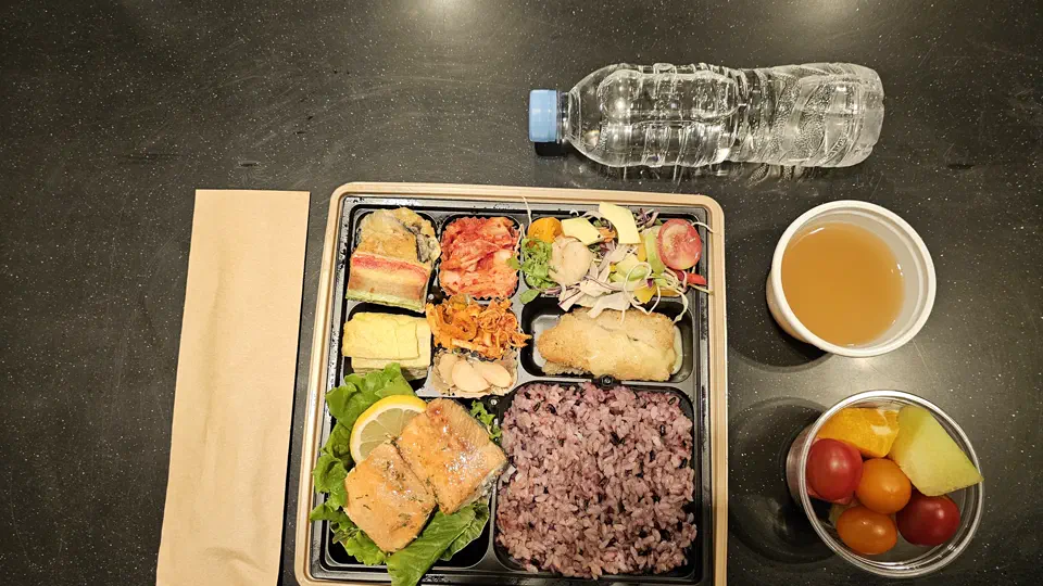 연어와 밥, 반찬, 과일, 국과 생수가 함께 준비된 실제 단체도시락